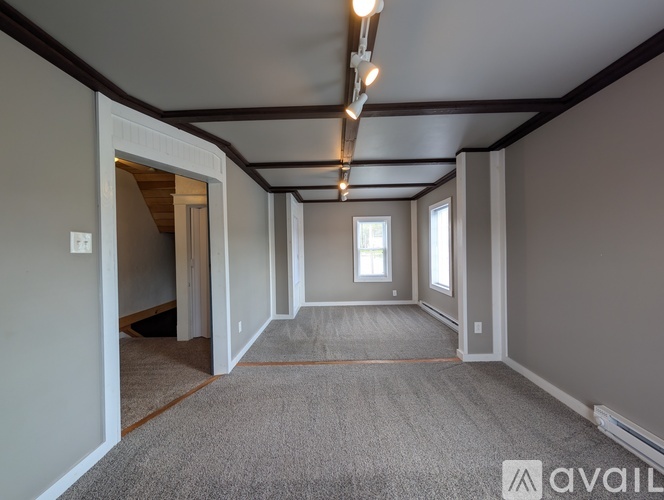A spacious room with a carpeted floor and a window letting in natural light.