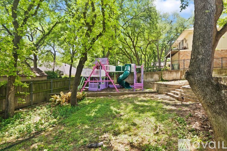 A playground with a pink swing set and a green slide.