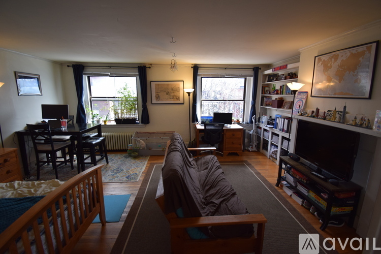 A living room with a couch, a chair, a table, a bookshelf, and a window.