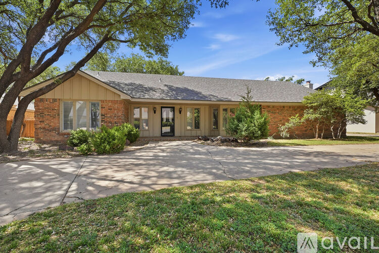 A house with a driveway and trees in front.