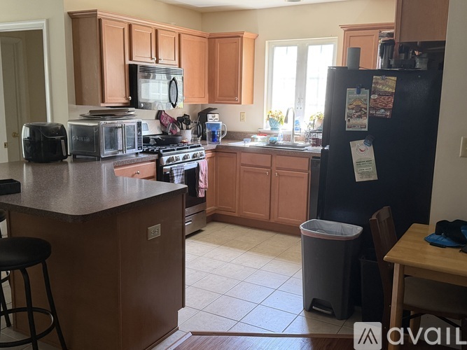 A kitchen with a black fridge and wooden cabinets.