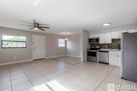 A spacious kitchen and living room with a ceiling fan and tiled flooring.