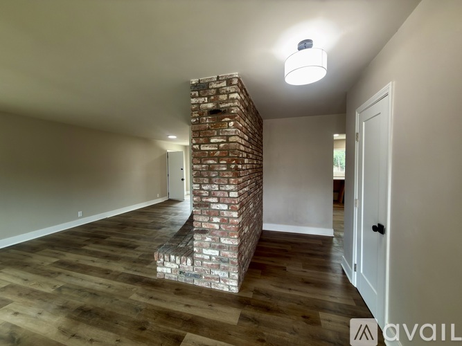 A room with a brick pillar and wooden flooring.
