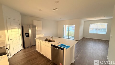 A kitchen with a sink, refrigerator, and a window.