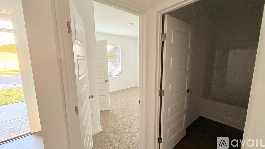 A hallway with a carpeted floor and white walls.