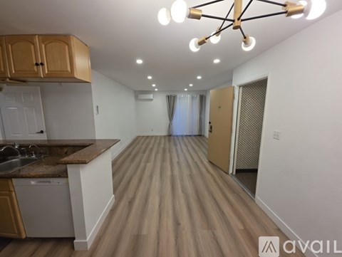 A kitchen with wooden floors and a modern ceiling light fixture.
