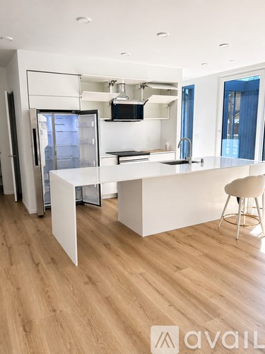 A modern kitchen with a white island and wooden flooring.