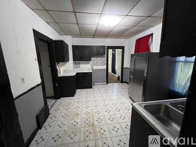 A kitchen with black cabinets and a tiled floor.