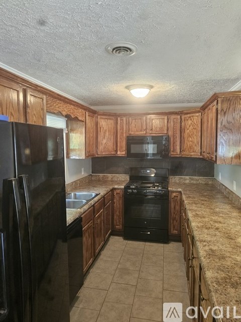 A kitchen with wooden cabinets and black appliances.