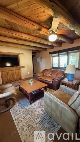 A living room with a brown leather couch and a wooden ceiling.