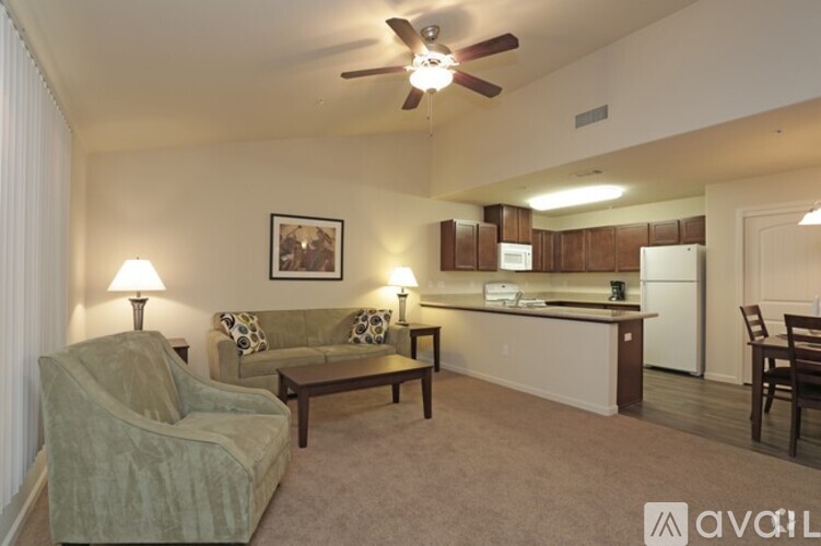 A living room with a couch, chairs, and a ceiling fan.