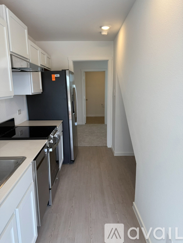 A kitchen with white cabinets and a black fridge.