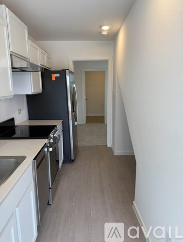 A kitchen with white cabinets and a black fridge.