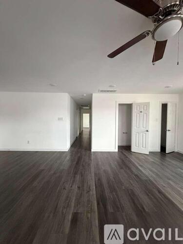 A room with a ceiling fan and wooden flooring.