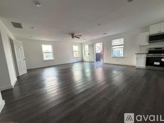 A spacious room with wooden flooring and a ceiling fan.