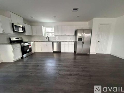 A kitchen with white cabinets and a wooden floor.