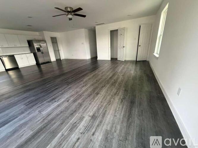 A spacious room with a ceiling fan and wooden flooring.