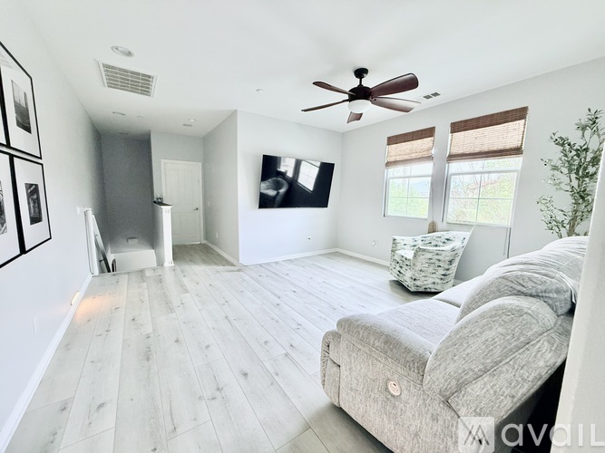 A living room with a grey couch and a ceiling fan.