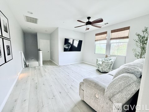 A living room with a grey couch and a ceiling fan.