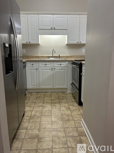 A kitchen with white cabinets and a tiled floor.