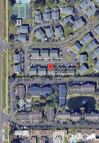 A satellite image of a residential area with a red marker indicating a specific house.