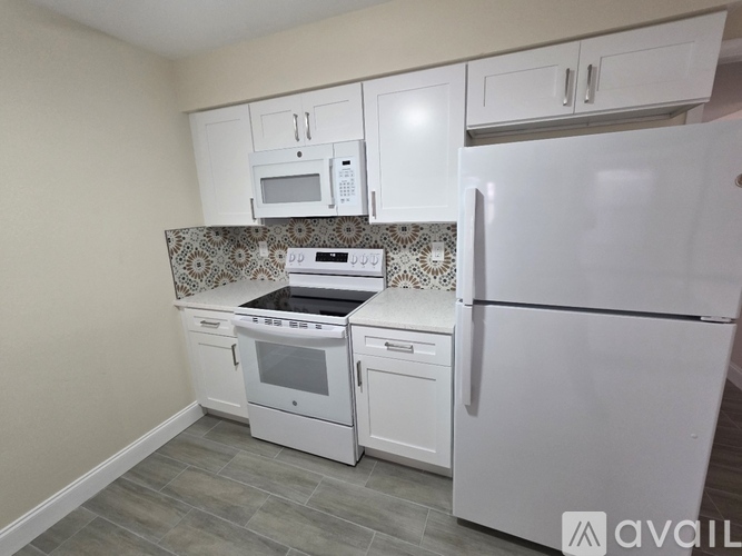 A kitchen with white appliances and a patterned backsplash.