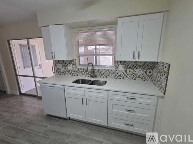 A kitchen with white cabinets and a patterned backsplash.