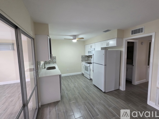A kitchen with a refrigerator, sink, and cabinets.