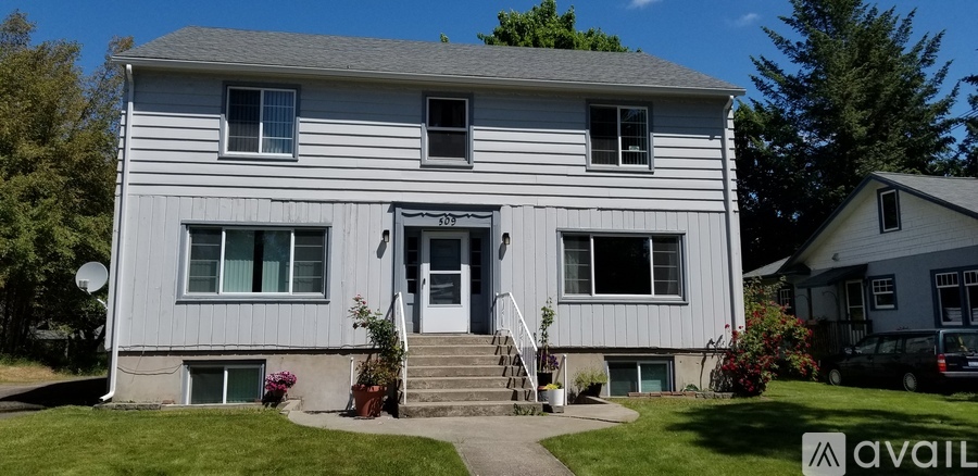 A two-story house with a grey siding exterior and a white door.
