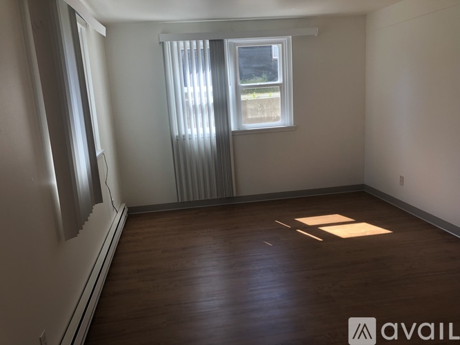A room with wooden floors and a window with blinds.