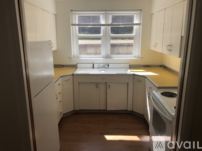 A kitchen with white cabinets and a window.