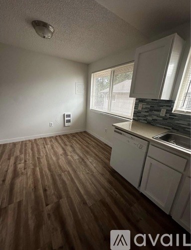 A kitchen with white cabinets and a wooden floor.
