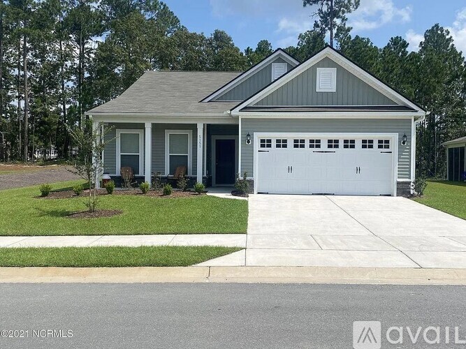 A house with a grey roof and a white garage door is available for sale.