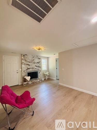 A living room with a red chair and a fireplace.