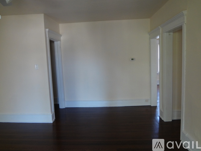 A room with white walls and dark wood flooring.