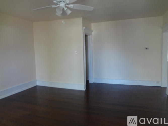 A room with a ceiling fan and wooden floors.
