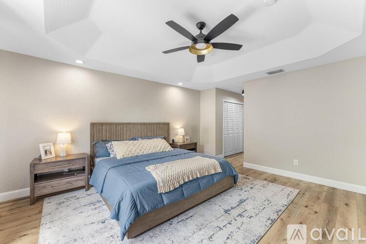 A bedroom with a large bed and a ceiling fan.