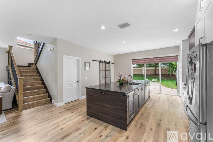 A kitchen with a wooden floor and a refrigerator on the right side.