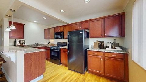 A kitchen with wooden cabinets and a black refrigerator.