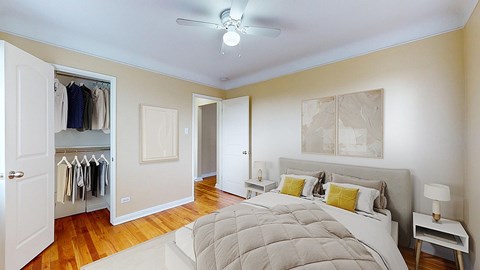 A bedroom with a large bed and a closet with clothes hanging.