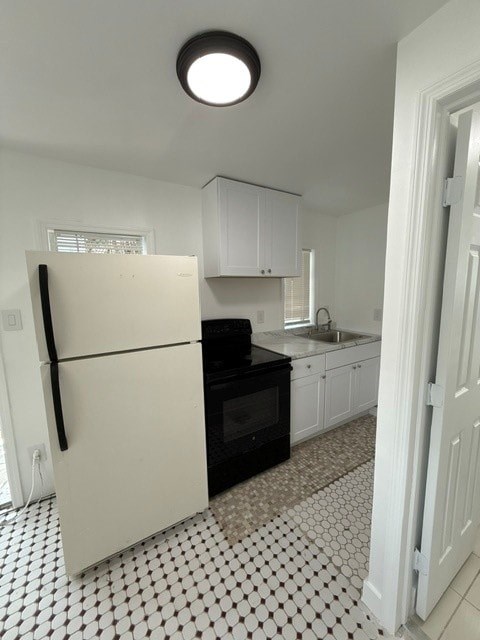 A white fridge in a kitchen with black and white tiles.