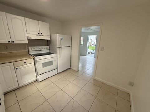 A kitchen with white cabinets and appliances.