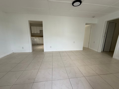 A spacious room with white walls and tiled flooring.