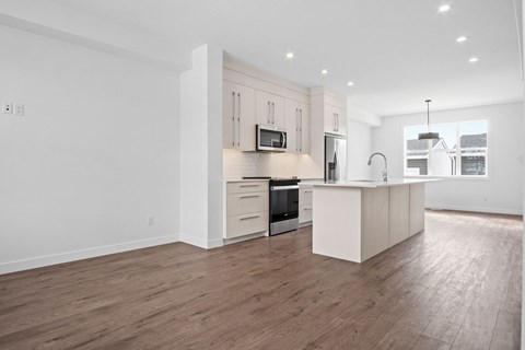 A modern kitchen with wooden floors and white cabinetry.