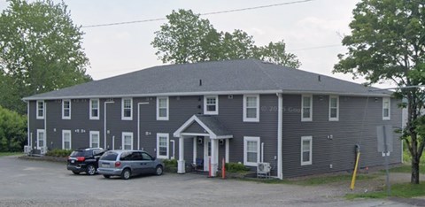 A grey building with a white door and windows.