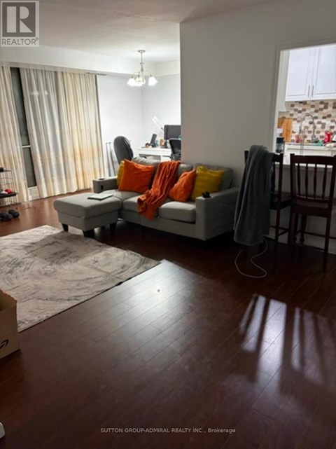 A living room with a grey couch and orange pillows.