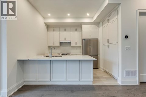 A kitchen with white cabinets and a stainless steel refrigerator.