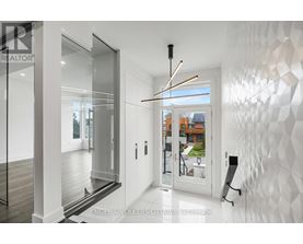 A modern interior space with a white geometric wall and a glass door leading to a balcony.