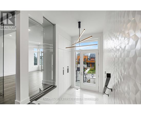 A modern interior space with a white geometric wall and a glass door leading to a balcony.