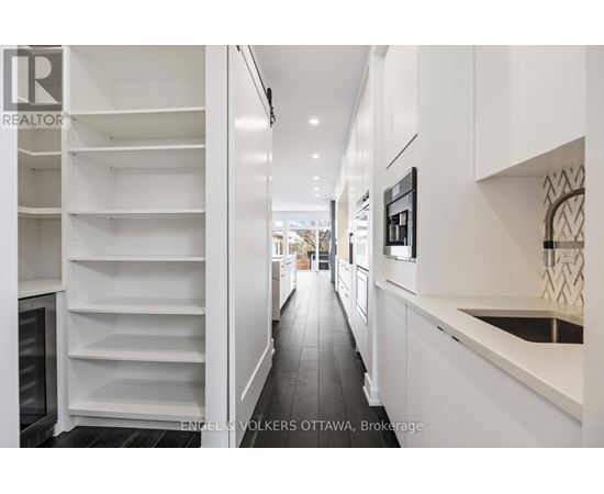 A modern kitchen with white cabinets and a black refrigerator.